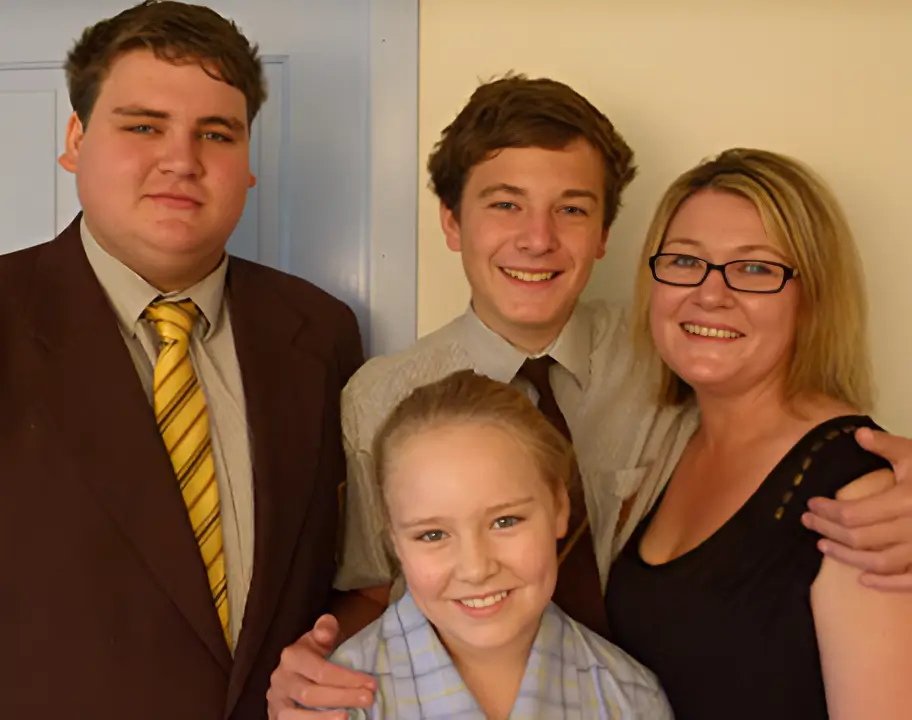 Family of four smiling together in a posed indoor photo.